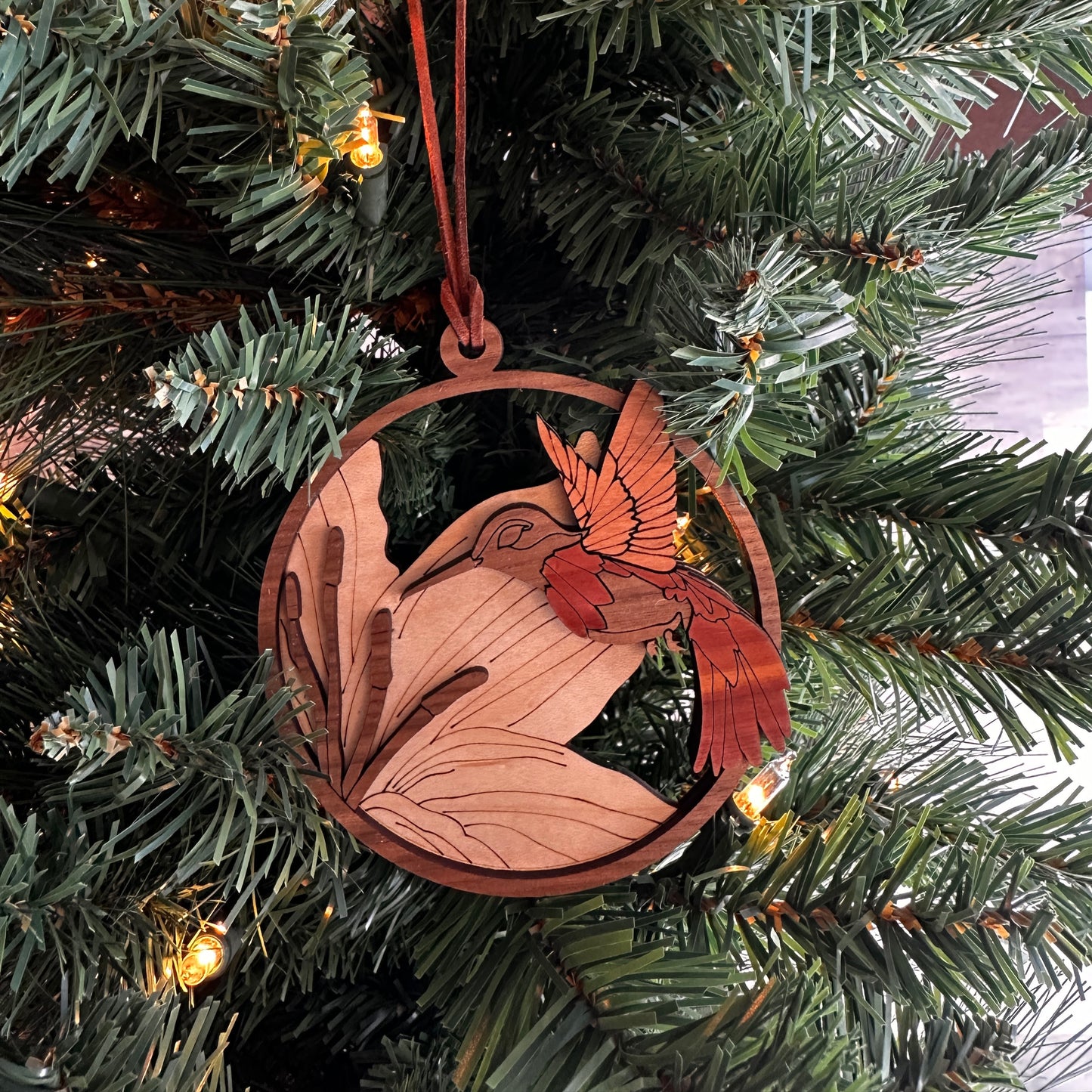 Layered wooden humming bird ornament made with multiple species of wood.